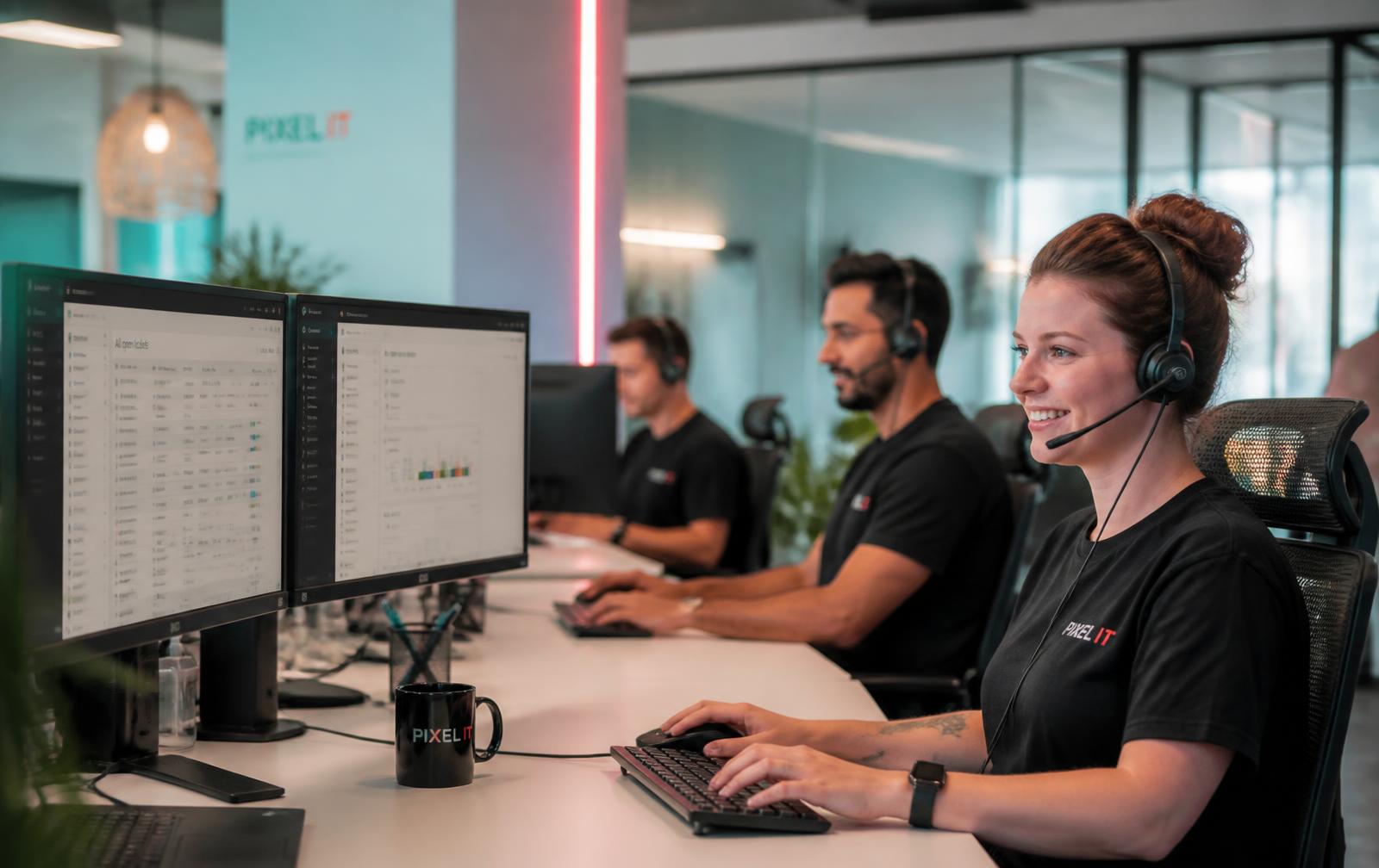 Support engineers wearing headsets working ticket queues and dashboards at a bright Australian service desk